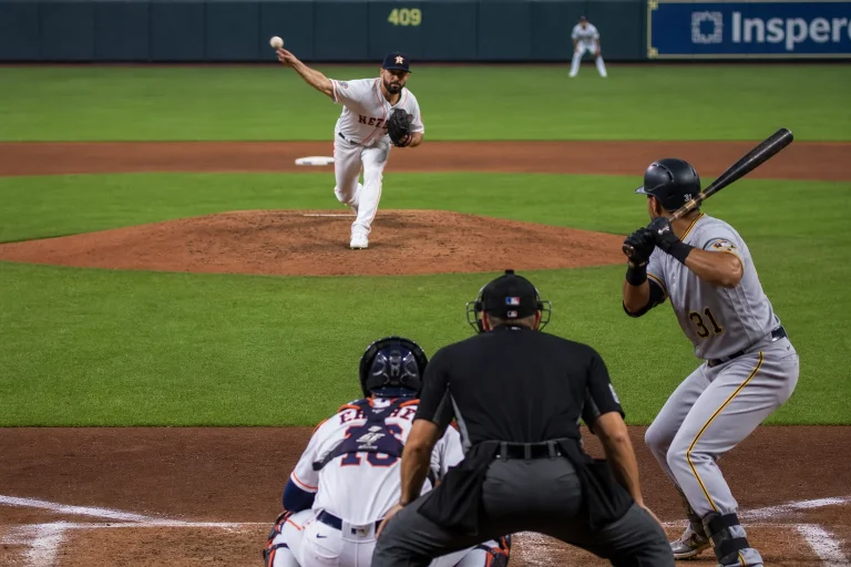 Pitcher mid-delivery firing a high fastball as the catcher's mitt frames the strike zone